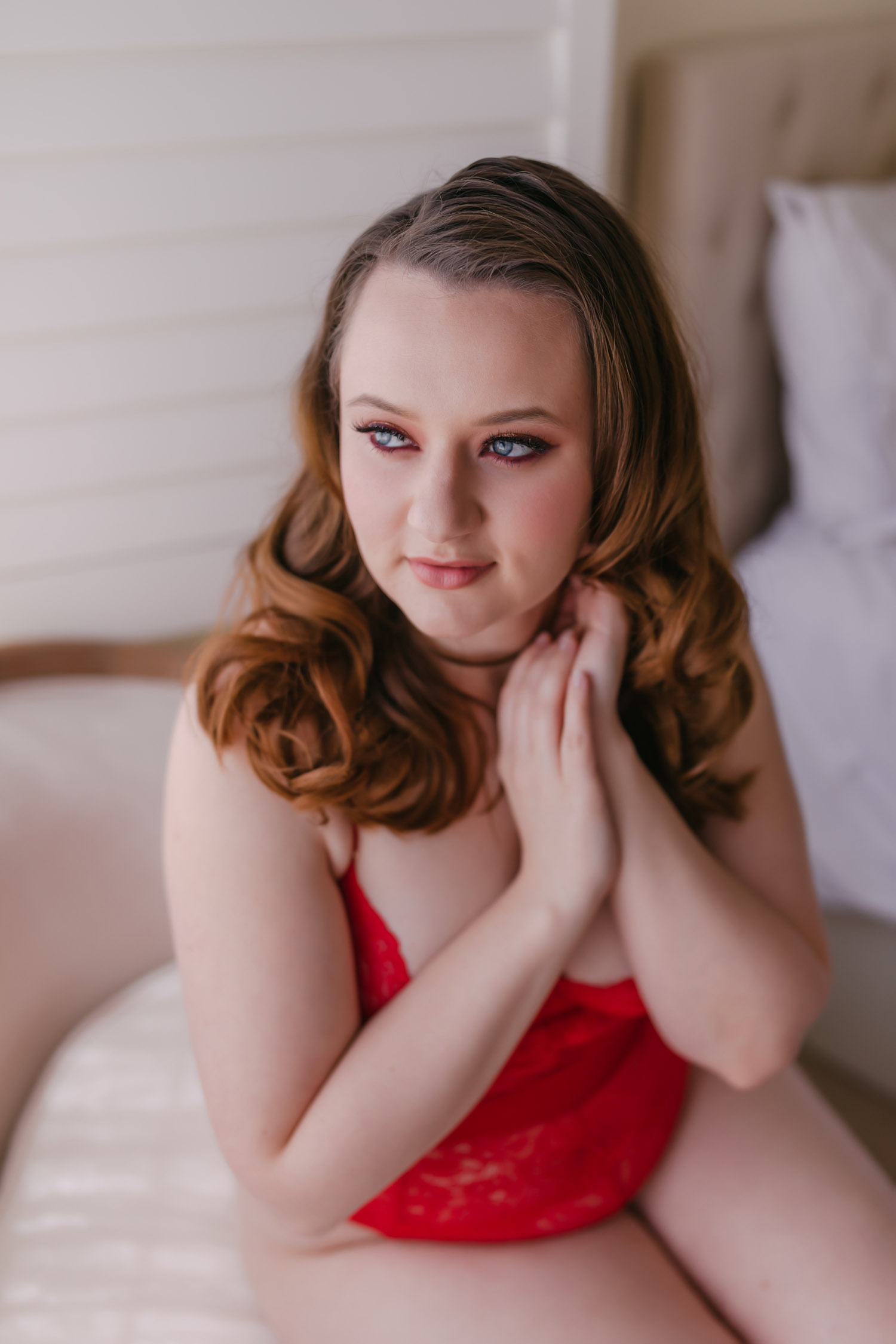 What is boudoir photography? Woman wearing red bodysuit looking out the window.